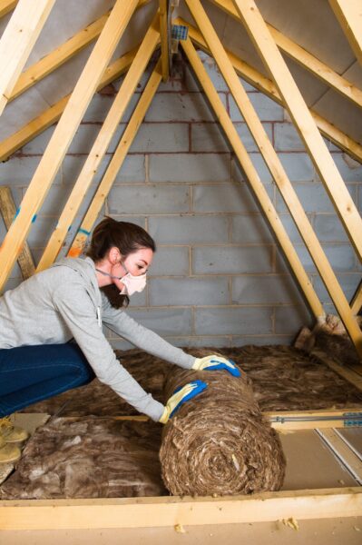 woman-installing-loft-insulation-roll